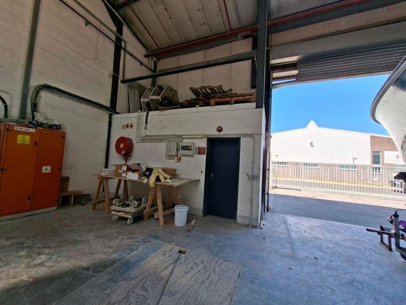 Industrial utility space featuring high ceilings, exposed steel structure, roller shutter access, and integrated electrical distribution infrastructure.