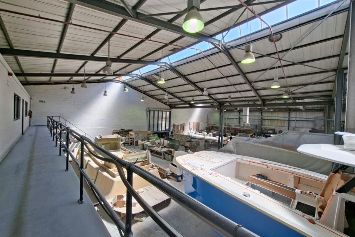 Spacious industrial workshop featuring a high-clearance steel truss roof with integrated skylights and a mezzanine level walkway overlooking the main floor area.