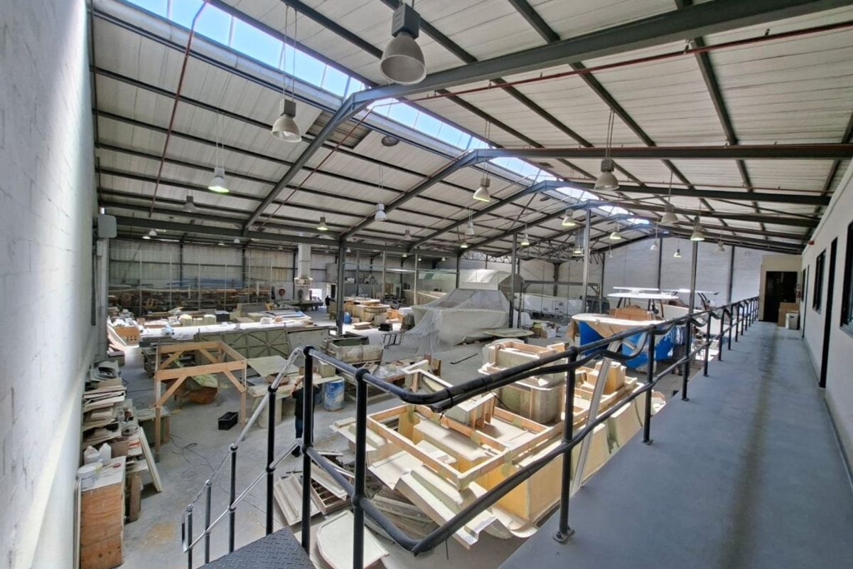 Spacious industrial workshop featuring a high-clearance steel truss roof with integrated skylights, mezzanine level, and durable concrete flooring suitable for manufacturing or storage.