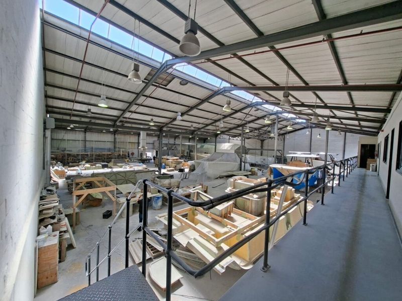 Spacious industrial workshop featuring a high-clearance steel truss roof with integrated skylights, mezzanine level, and durable concrete flooring suitable for manufacturing or storage.
