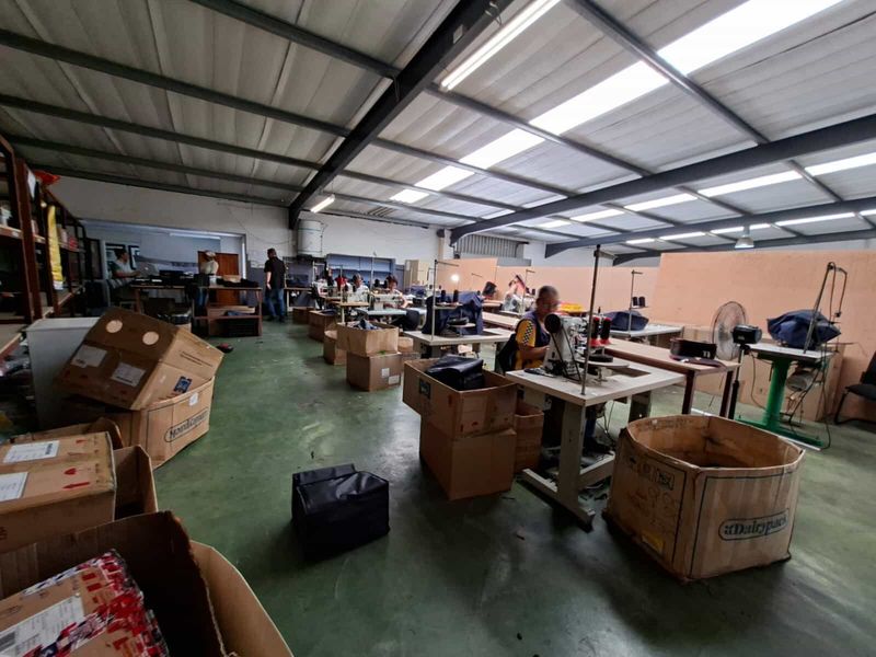 Spacious industrial workshop area featuring high ceilings with exposed steel trusses, translucent roof panels for natural light, and durable painted concrete flooring.