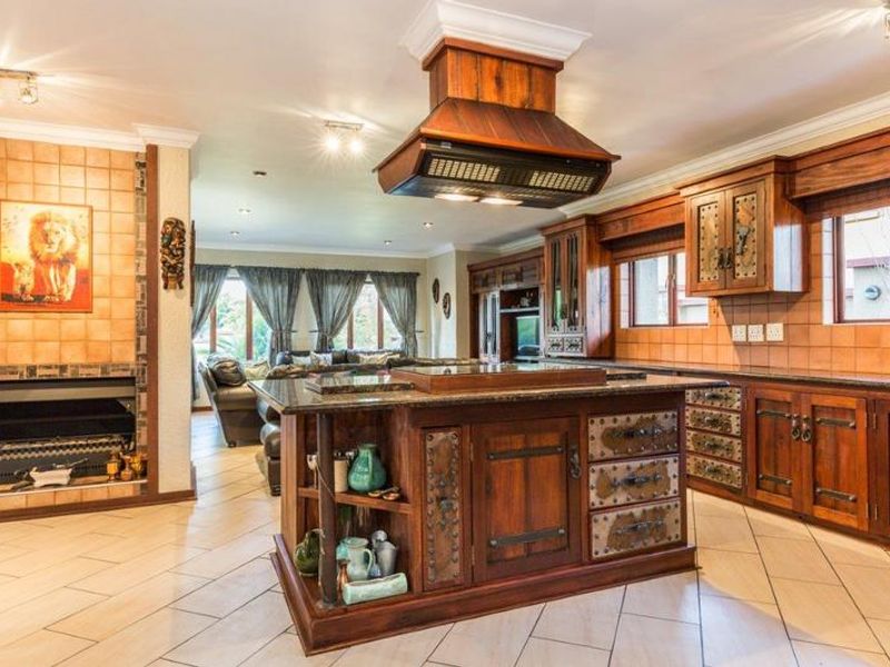 Spacious open-plan kitchen and living area featuring custom wooden cabinetry, a central island with granite countertops, and a built-in fireplace.