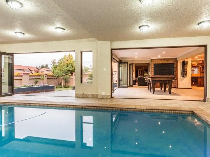 Covered patio area overlooking a swimming pool with large bi-fold doors providing seamless indoor-outdoor flow to the living spaces.