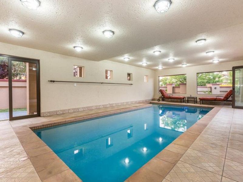 Spacious indoor swimming pool area featuring tiled flooring, multiple recessed ceiling lights, and large sliding glass doors providing access to the exterior.