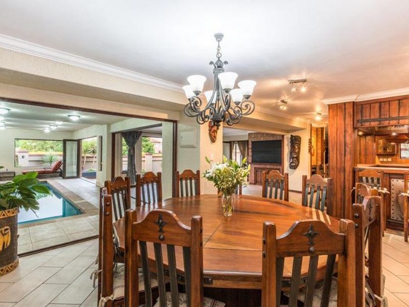 Spacious open-plan dining and entertainment area featuring a built-in bar, tiled floors, and seamless access to the indoor swimming pool area.