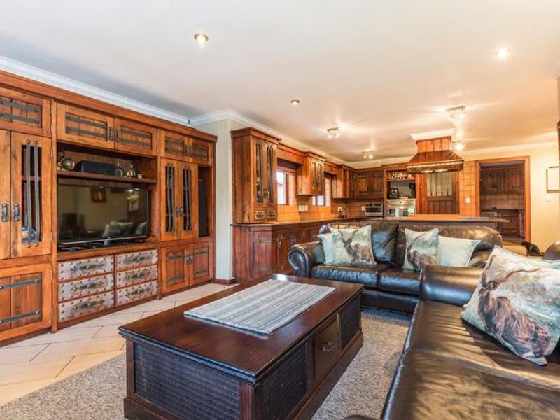 Spacious open-plan living area featuring extensive built-in wooden cabinetry, integrated kitchen appliances, and tiled flooring, creating a cohesive and functional living and dining space.