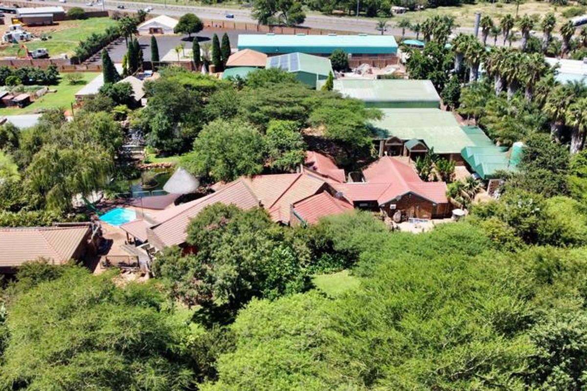 An aerial view of the small holding property, showcasing the main dwelling, swimming pool, extensive garden, and surrounding outbuildings.