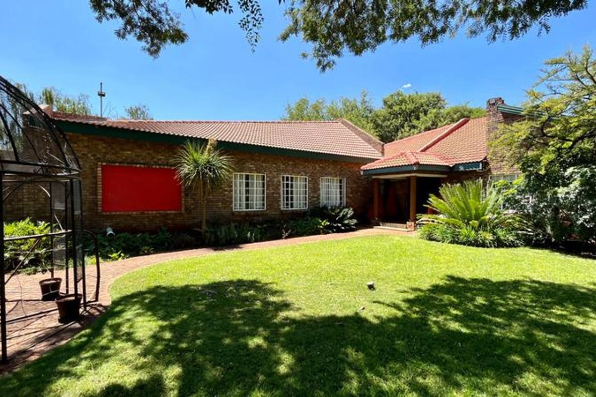 A view of the rear garden and brick facade of the small holding, featuring a well-maintained lawn and paved pathway.