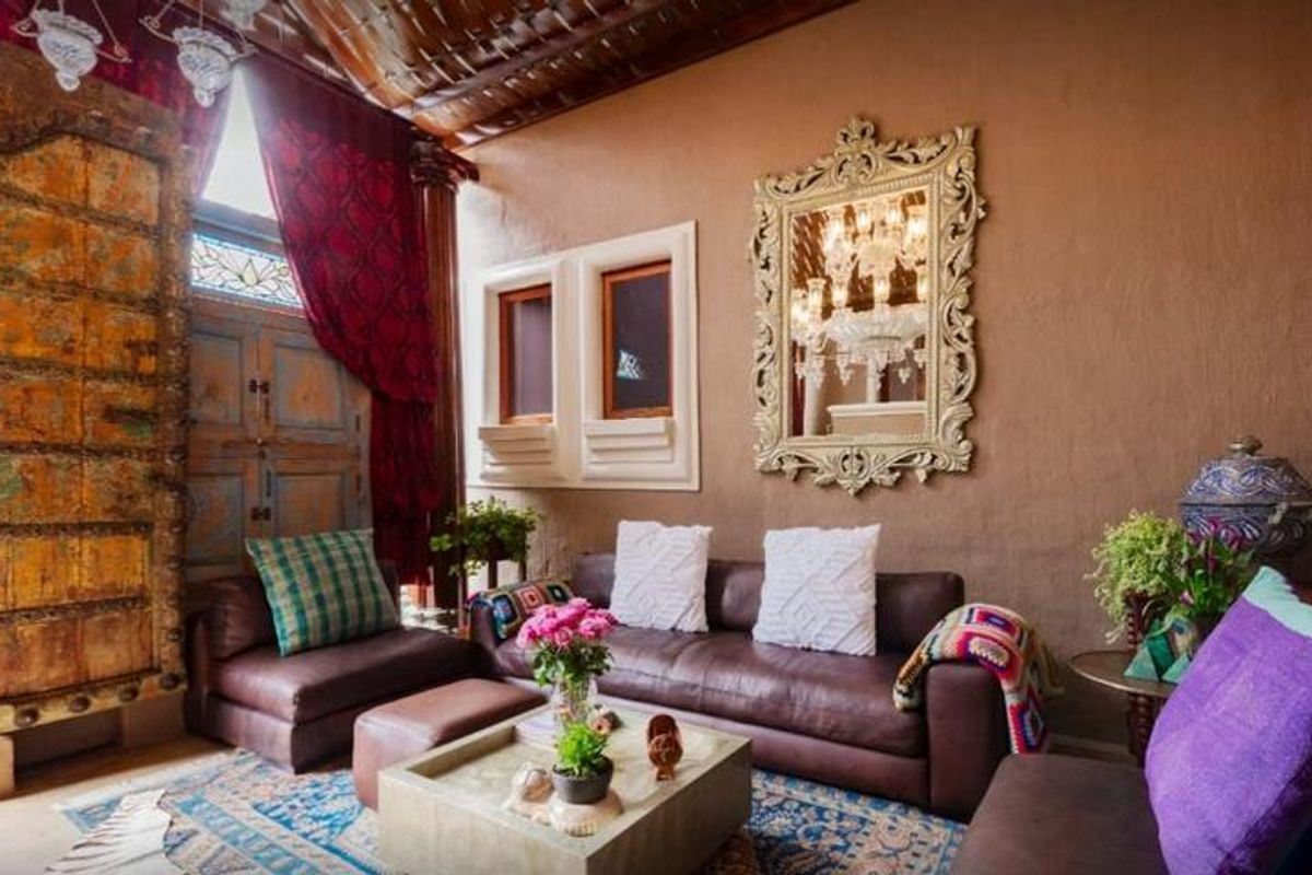 A characterful living room featuring a high ornate wooden ceiling, a large antique carved wooden door, and unique architectural wall niches.