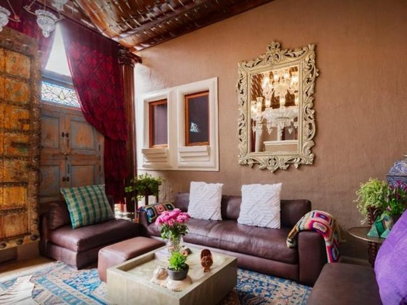 A characterful living room featuring a high ornate wooden ceiling, a large antique carved wooden door, and unique architectural wall niches.