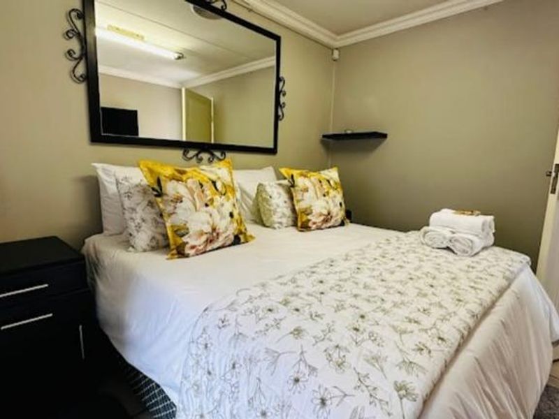 A well-maintained guest bedroom featuring neutral wall tones, crown molding, and tiled flooring, providing a comfortable and functional space for guests.