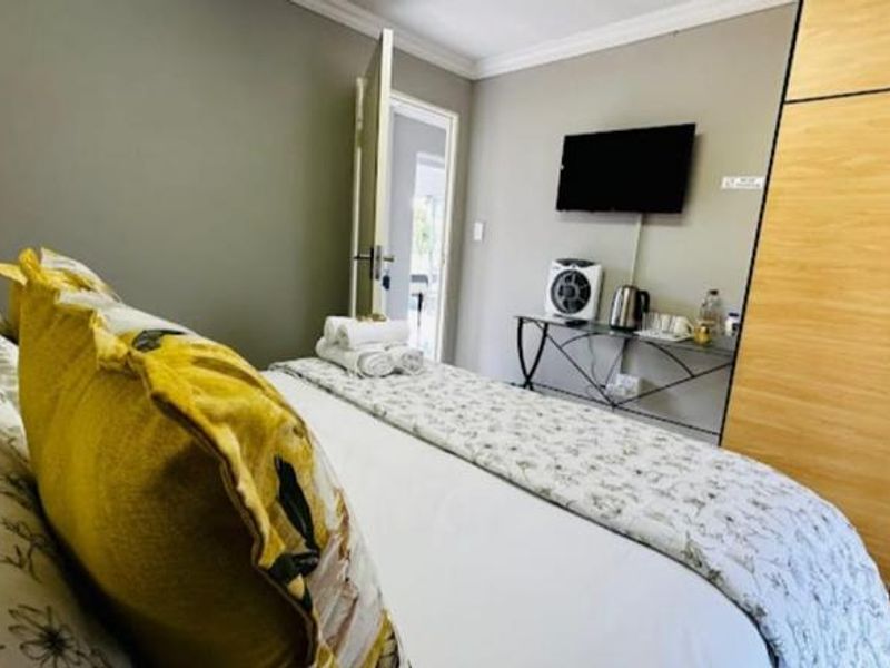 A functional bedroom featuring a built-in wooden wardrobe and crown molding, providing a comfortable space for guests.