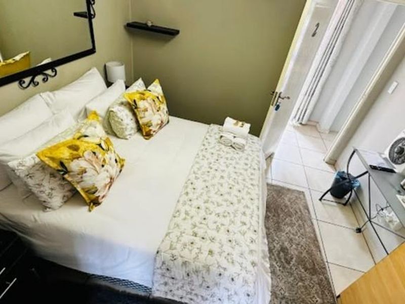 A well-maintained guest bedroom featuring tiled flooring, a wall-mounted television, and neutral wall finishes, providing a comfortable and functional space for guests.