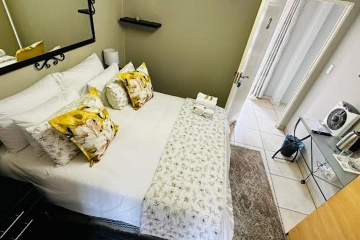 A well-maintained guest bedroom featuring tiled flooring, a wall-mounted television, and neutral wall finishes, providing a comfortable and functional space for guests.