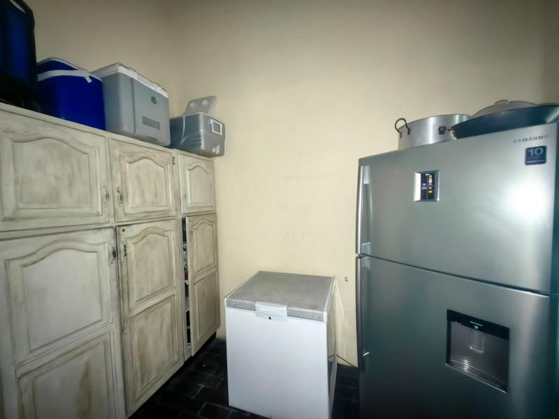 A functional scullery or utility area featuring built-in cabinetry and tiled flooring, providing additional storage and workspace.