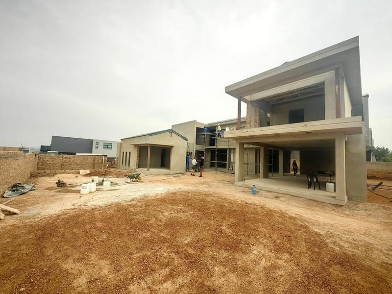 Rear view of a double-story residential property currently under construction, featuring a covered patio area and unfinished exterior surfaces.