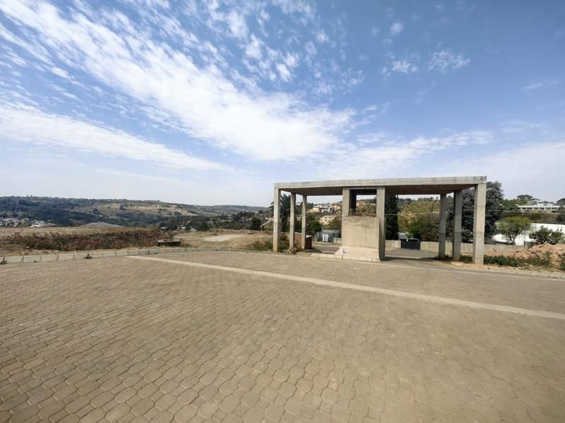 An expansive paved driveway area featuring an unfinished concrete structural frame, set against a scenic landscape view.