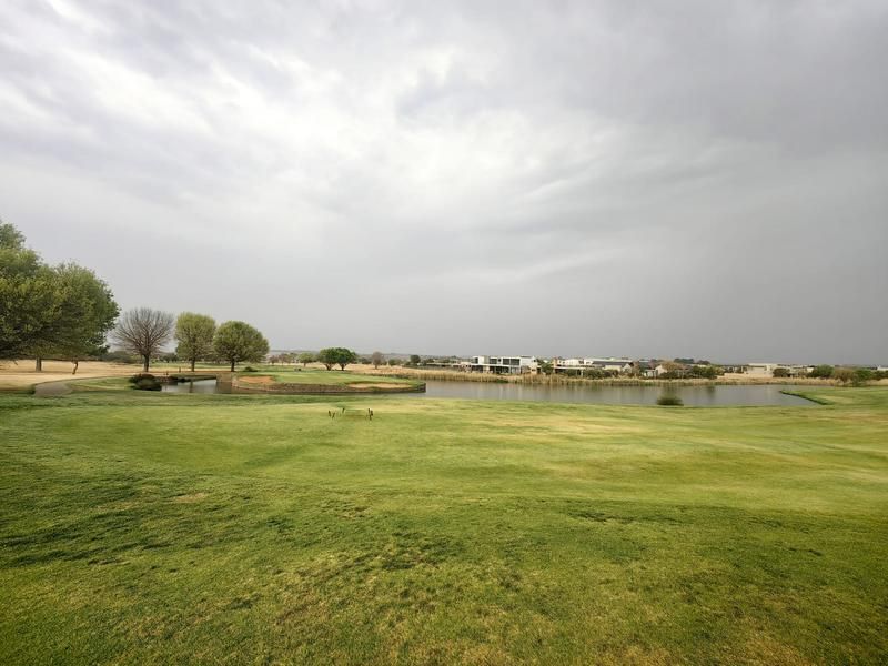 A scenic view overlooking a golf course fairway and a tranquil lake, showcasing the surrounding estate landscape.