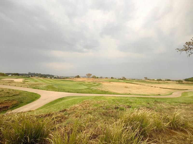 A scenic view overlooking a well-maintained golf course with a paved cart path winding through the landscape.