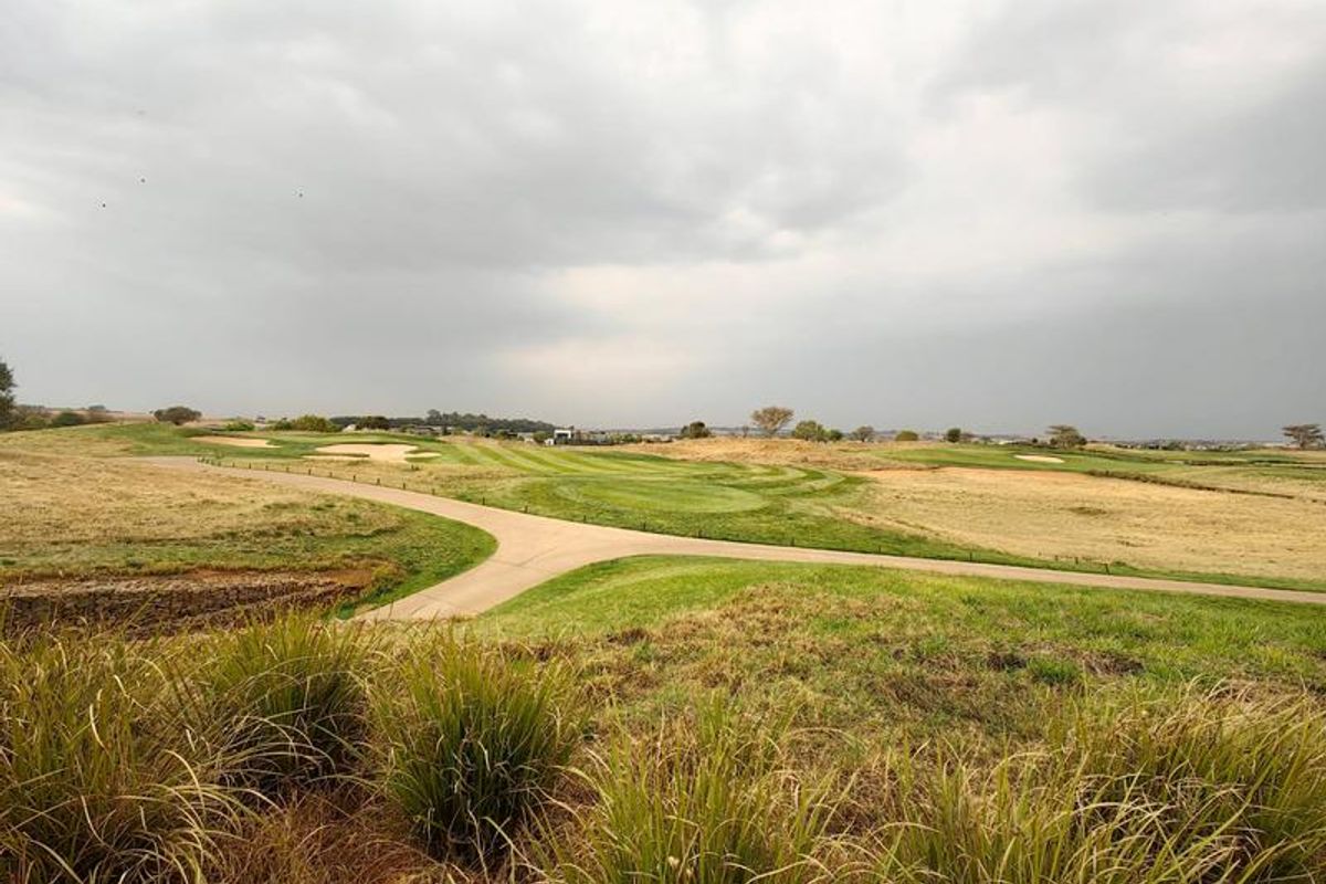 Expansive scenic view overlooking a well-maintained golf course with a paved cart path winding through the landscape.