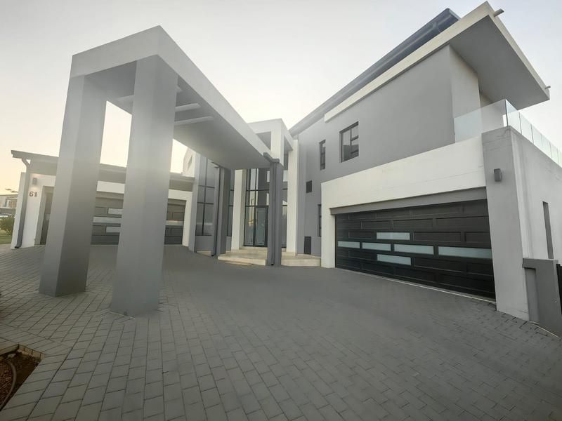 Modern double-story residence featuring a striking architectural facade, paved driveway, and integrated double garage with a prominent covered entrance portico.