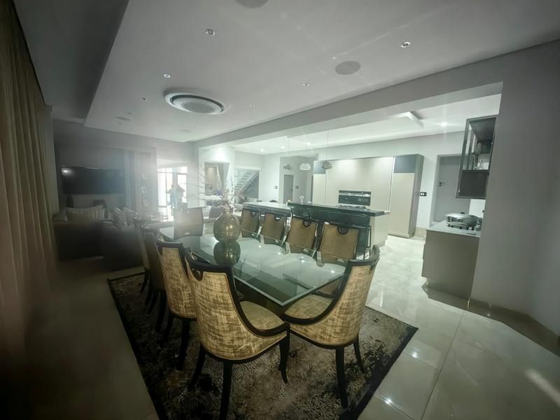 Spacious open-plan living and dining area featuring modern kitchen cabinetry, integrated appliances, recessed ceiling lighting, and sleek tiled flooring throughout.