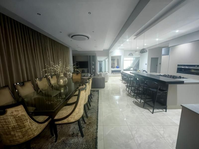 Spacious open-plan living, dining, and kitchen area featuring modern finishes, large porcelain floor tiles, recessed lighting, and a sleek kitchen island with integrated appliances.