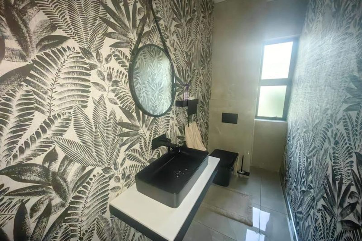 Modern bathroom featuring a wall-mounted vanity with a black vessel sink, wall-hung toilet, and striking botanical patterned wallpaper.