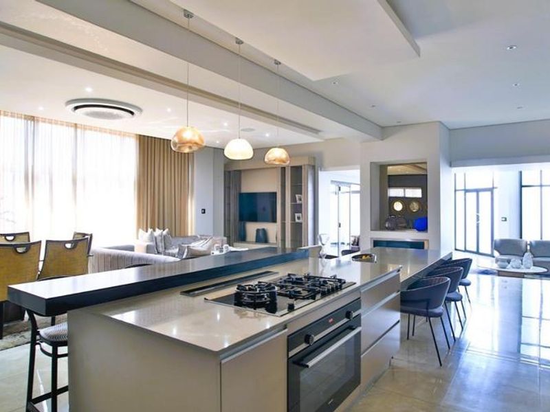 Modern open-plan living area featuring a sleek kitchen island with integrated gas cooktop and oven, complemented by recessed lighting and high-end finishes.