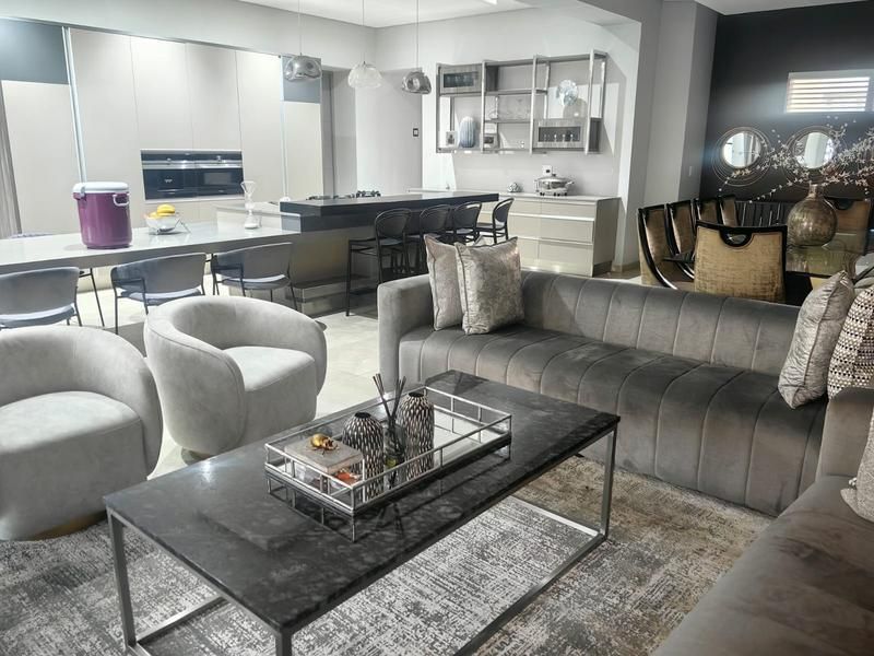 Modern open-plan living area featuring a sleek kitchen with integrated appliances, a central island, and a spacious lounge area with contemporary finishes.