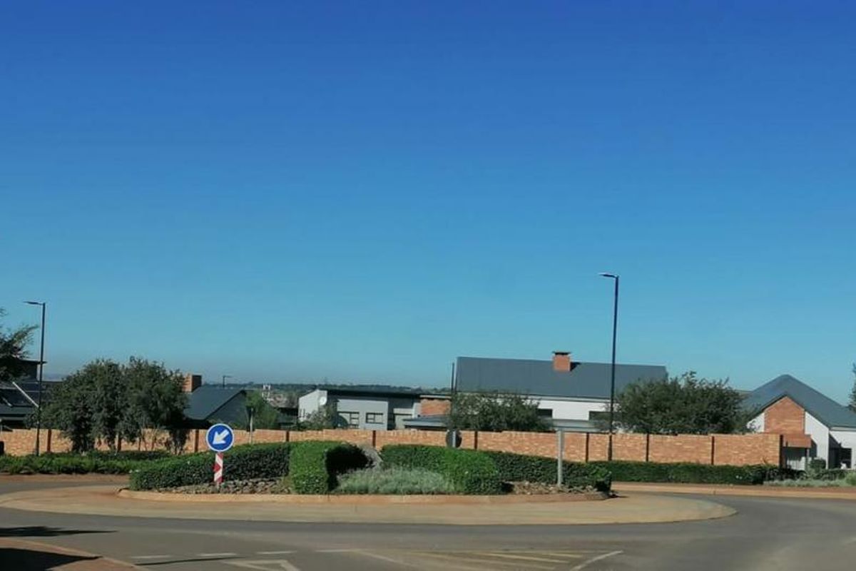 A view of the residential estate entrance featuring a landscaped roundabout and brick boundary wall.