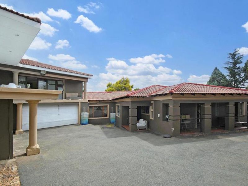 Front exterior view of the property featuring a paved driveway, covered patio area, and integrated garage with tiled roofing.