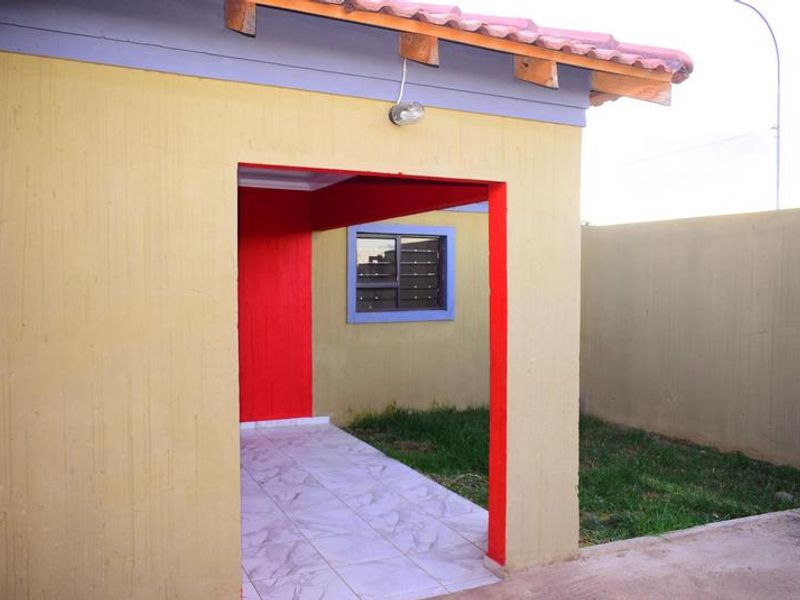 A rear exterior view featuring a small tiled patio area, perimeter wall, and terracotta roof tiles, showing signs of wear on the exterior paintwork.
