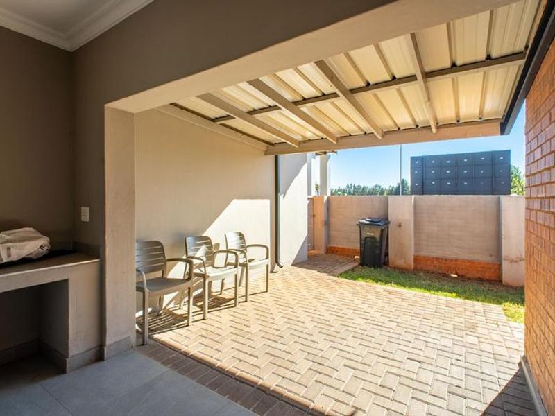 A covered patio area featuring paved flooring and a built-in braai, providing a functional outdoor space for entertaining.