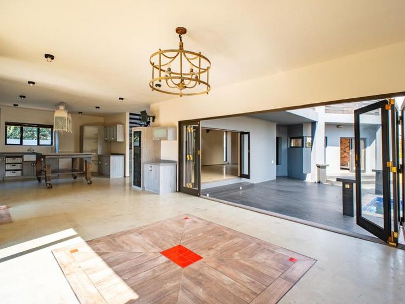 Spacious open-plan living area featuring a modern kitchen, decorative floor inlay, and large bi-fold doors opening onto an outdoor deck.