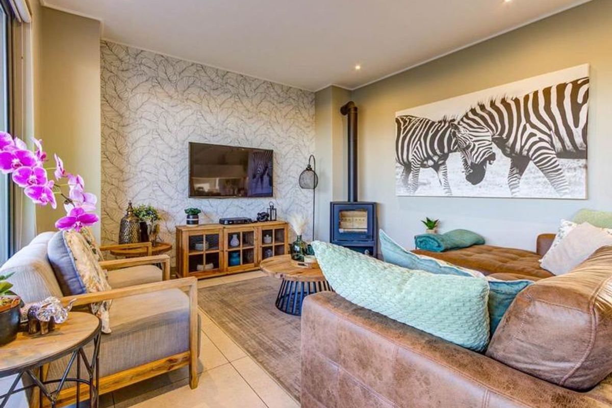 A well-maintained living room featuring a modern freestanding fireplace, tiled flooring, and a decorative feature wall.
