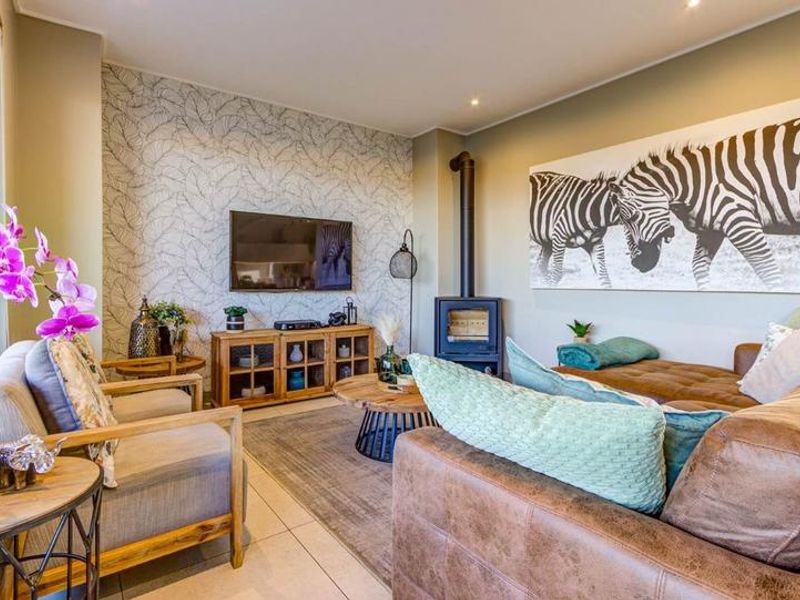 A well-maintained living room featuring a modern freestanding fireplace, tiled flooring, and a decorative feature wall.