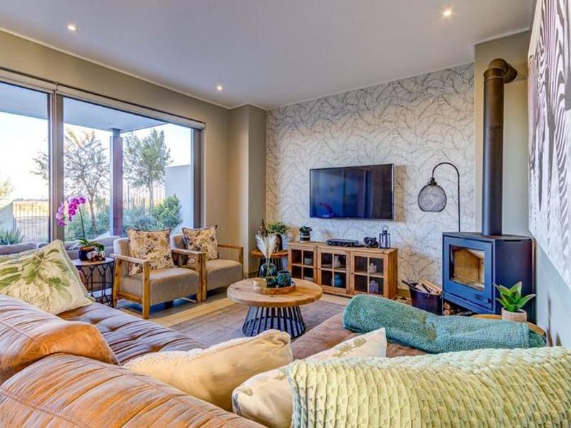 A modern living room featuring a freestanding fireplace, feature wallpaper, and large sliding glass doors that provide ample natural light and garden access.