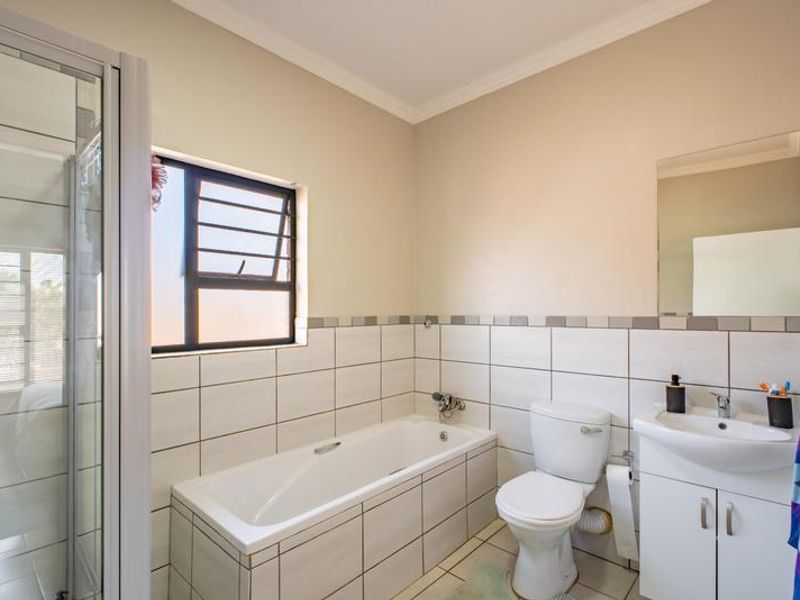 A functional bathroom featuring a shower enclosure, bathtub, toilet, and a vanity basin with storage cabinetry.