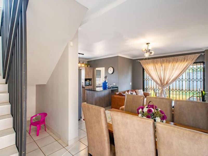 Open plan living and dining area featuring a tiled staircase, modern kitchen cabinetry with an island, and direct access to the rear garden.