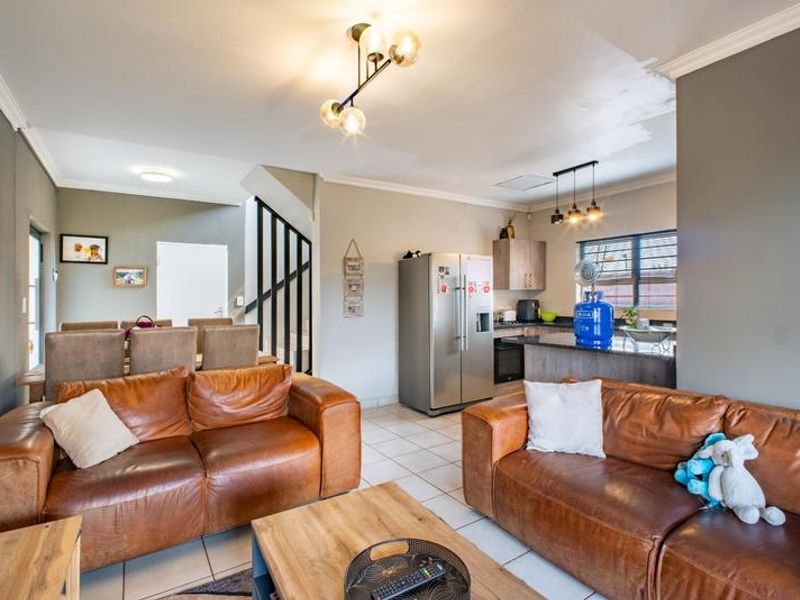 Open-plan living and kitchen area featuring tiled floors, a central kitchen island, and a staircase, with some minor ceiling paint touch-ups required.