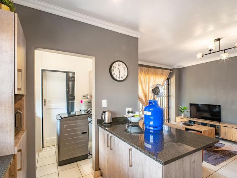 Open plan living area featuring a kitchen island with granite countertops, tiled flooring, and neutral wall finishes, seamlessly connecting to the adjacent living space.