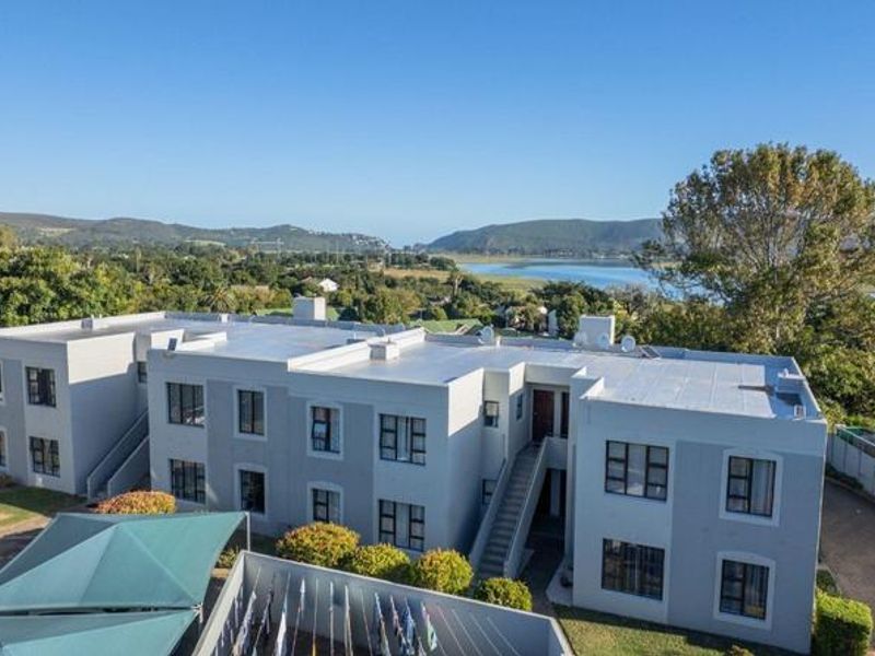 Aerial view of a multi-story apartment complex featuring flat roofs, external staircases, and scenic views of the surrounding landscape and water.