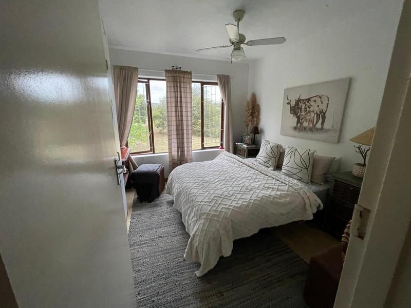 A cozy bedroom featuring a ceiling fan and a large window providing natural light and outdoor views.