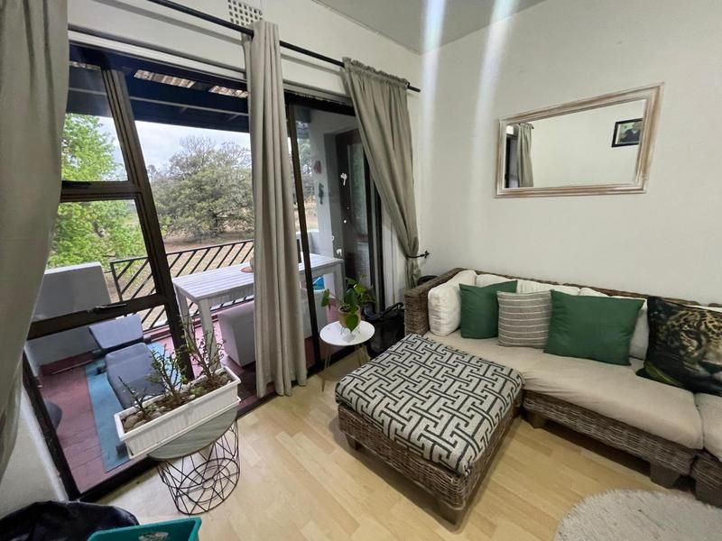 Living room area featuring laminate flooring and large sliding glass doors providing direct access to an outdoor balcony space.