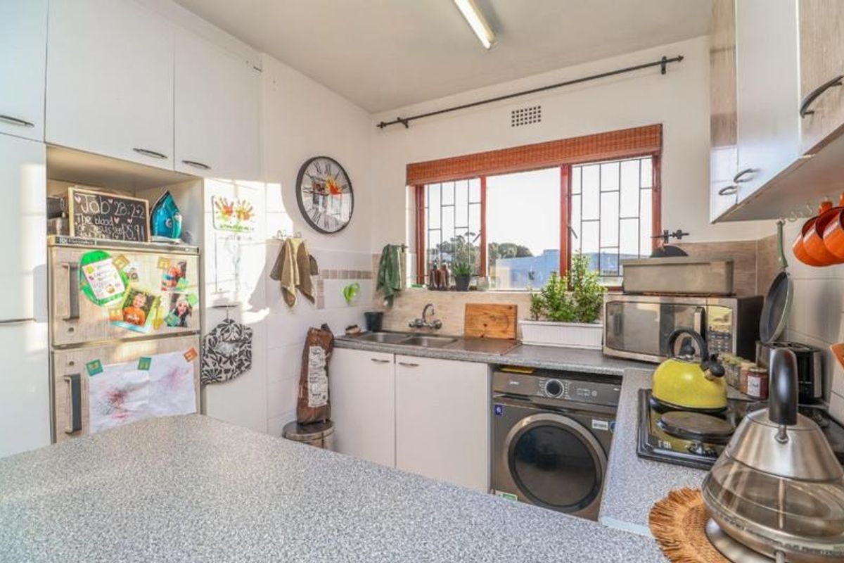 Functional kitchen featuring laminate countertops, built-in cabinetry, a double bowl sink, and a built-in hob with integrated laundry appliance space.