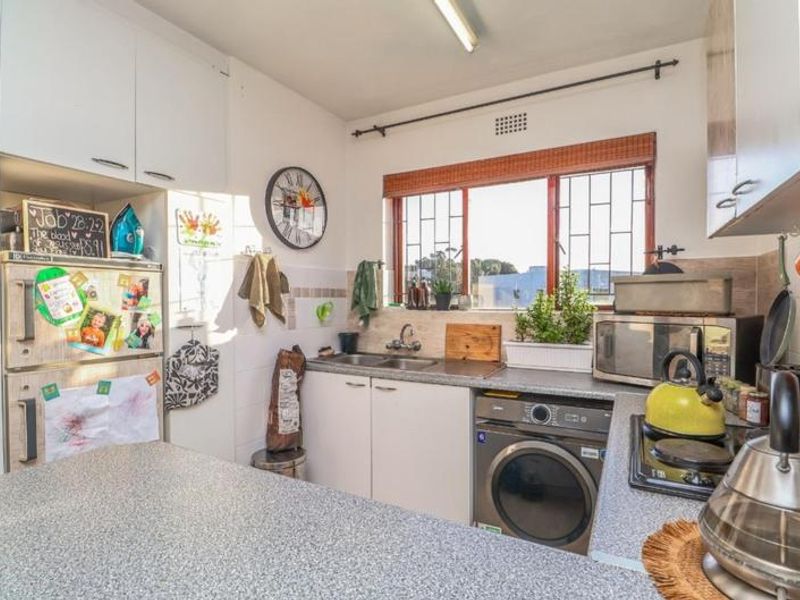 Functional kitchen featuring laminate countertops, built-in cabinetry, a double bowl sink, and a built-in hob with integrated laundry appliance space.