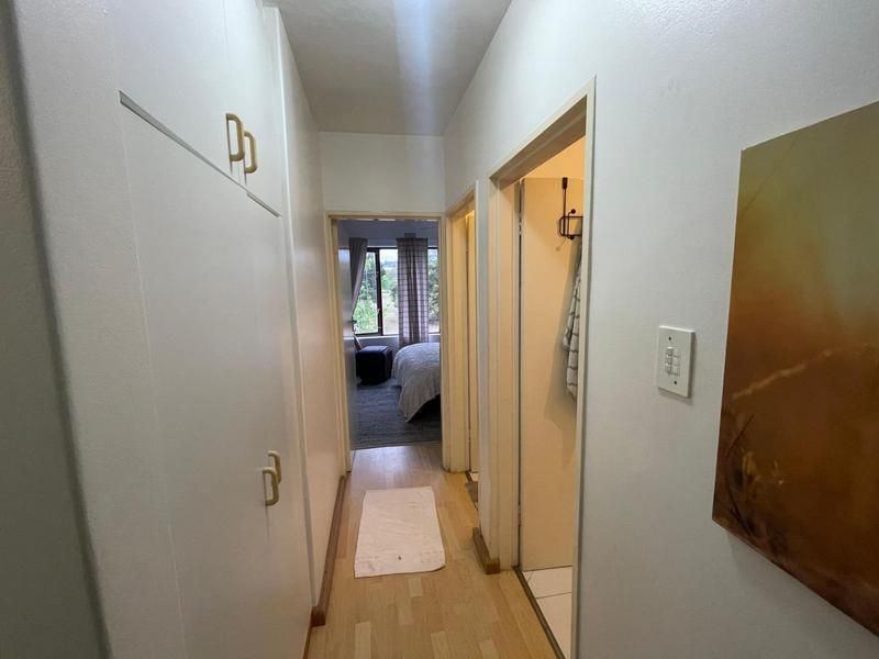 A functional hallway featuring built-in storage cupboards and light-toned laminate flooring, providing access to adjacent rooms.