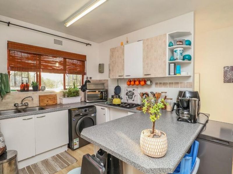 Functional kitchen featuring laminate countertops, built-in cabinetry, a gas hob, and a double sink with natural light from the window.
