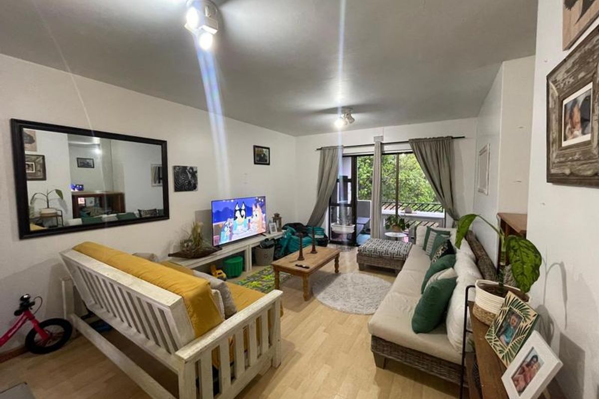 A comfortable living room featuring laminate flooring and a sliding glass door that provides access to an outdoor balcony area.